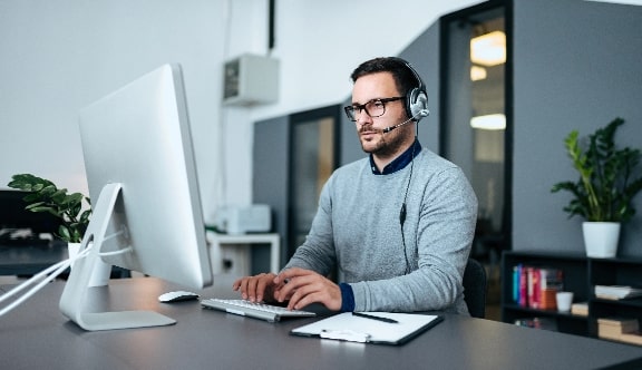 Young customer support specialist with headset working on computer